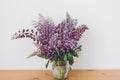 Beautiful lupine bouquet on wooden table in white room. Gathering wildflowers. Purple lupine flowers Royalty Free Stock Photo