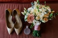 Beautiful lush wedding bouquet near the bride`s shoes and perfume in blur.