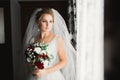 Beautiful luxury bride in elegant white dress holds bouquet of flowers in the hands