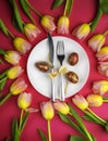 Easter table cutlery with tulips and eggs on red background Royalty Free Stock Photo