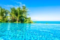 Beautiful luxury outdoor swimming pool in hotel resort with sea ocean around coconut palm tree and white cloud on blue sky Royalty Free Stock Photo