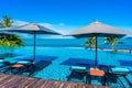 Beautiful luxury outdoor swimming pool in hotel resort with sea ocean around coconut palm tree and white cloud on blue sky Royalty Free Stock Photo