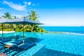 Beautiful luxury outdoor swimming pool in hotel resort with sea ocean around coconut palm tree and white cloud on blue sky Royalty Free Stock Photo