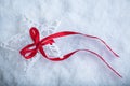 Beautiful magical vintage white star tied with a red ribbon on a white snow background. Winter and Christmas concept Royalty Free Stock Photo