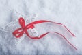 Beautiful magical vintage white star tied with a red ribbon on a white snow background. Winter and Christmas concept. Royalty Free Stock Photo