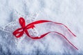 Beautiful magical vintage white star tied with a red ribbon on a white snow background. Royalty Free Stock Photo