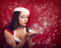 Beautiful makeup happy woman in santa claus costume blowing on s Royalty Free Stock Photo