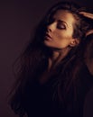 Beautiful makeup woman with brown long hair looking on dark shadow background. Closeup toned portrait. Art .Expression