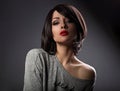 Beautiful makeup woman with short hair style and hot red lipstick posing with nude shoulder on dark shadow background. Close Royalty Free Stock Photo