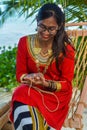 Beautiful maldivian girl in national dress crafting hand made rope