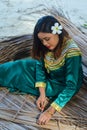 Beautiful maldivian lady in national dress making sheets for roof
