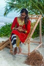 Beautiful maldivian woman in national dress making hand made rope