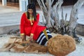 Beautiful maldivian woman in national red dress making hand made rope