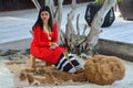 Beautiful maldivian woman in national red dress making ropes