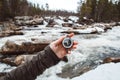 Beautiful male hand holds a magnetic compass against the background of mountain river, rocks and forest. The concept of finding Royalty Free Stock Photo