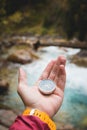 A beautiful male hand with a yellow watch strap holds a magnetic compass in a coniferous autumn forest against a Royalty Free Stock Photo