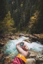 A beautiful male hand with a yellow watch strap holds a magnetic compass in a coniferous autumn forest against a Royalty Free Stock Photo