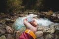 A beautiful male hand with a yellow watch strap holds a magnetic compass in a coniferous autumn forest against a Royalty Free Stock Photo