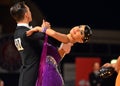 Beautiful man and woman in violet dress perform smiling during dancesport competition Royalty Free Stock Photo