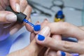 Beautiful manicure process. Nail polish being applied to hand, polish is a blue color. close up