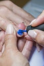 Beautiful manicure process. Nail polish being applied to hand, polish is a blue color. close up. vertical photo