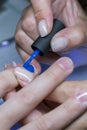 Beautiful manicure process. Nail polish being applied to hand, polish is a blue color. closeup. vertical photo