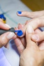 Beautiful manicure process. Nail polish being applied to hand, polish is a blue color. closeup. vertical photo