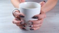 Beautiful manicured nails in the form of chocolate candies on female hands close-up and a cup of coffee.