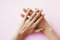 Beautiful manicured woman hands on pink background, wearing wedding ring