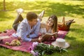 Beautiful married couple reading book while lying on picnic blanket in park Royalty Free Stock Photo