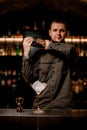 beautiful martini glass with ice and jigger stands on bar. Blurred bartender in background Royalty Free Stock Photo