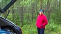 Beautiful mature athletic woman stands near the car in the forest on a summer day Royalty Free Stock Photo