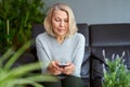 Beautiful mature blond woman talking on mobile phone at sofa. Royalty Free Stock Photo