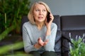 Beautiful mature blond woman talking on mobile phone at sofa. Royalty Free Stock Photo