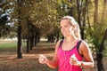 Beautiful mature blonde woman running at the park on a sunny day. Female runner listening to music while jogging Royalty Free Stock Photo