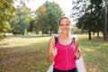 Beautiful mature blonde woman running at the park on a sunny day. Female runner listening to music while jogging Royalty Free Stock Photo