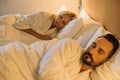 beautiful mature couple in bathrobes sleeping together in bed in hotel Royalty Free Stock Photo