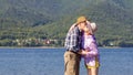 Mature sportive couple walks along the sandy river bank on a summer sunny day with mountains in the background Royalty Free Stock Photo