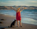 Mature woman and pet dog walking together on empty beach in the new normal after coronavirus Royalty Free Stock Photo