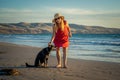 Mature woman and pet dog walking together on empty beach in the new normal after coronavirus Royalty Free Stock Photo