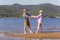 Beautiful mature sportive couple walks along the sandy river bank on a summer sunny day with mountains Royalty Free Stock Photo