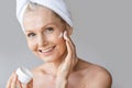 Beautiful mature woman applying moisturizing cream under her eyes, making beauty treatment with cosmetic product Royalty Free Stock Photo