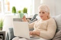 Beautiful mature woman drinking coffee while using laptop at home Royalty Free Stock Photo