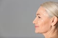 Beautiful mature woman after facelift cosmetic surgery procedure on grey background. Space for text