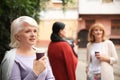 Beautiful mature woman and her friends drinking coffee outdoors Royalty Free Stock Photo