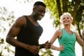 Beautiful mature woman jogging with trainer outdoors in park Royalty Free Stock Photo