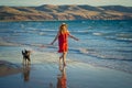 Happy attractive mature woman with her pet walking on friendly dog beach at sunset Royalty Free Stock Photo