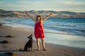 Happy attractive mature woman with her pet walking on friendly dog beach at sunset Royalty Free Stock Photo