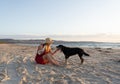 Happy attractive mature woman with her pet walking on friendly dog beach at sunset Royalty Free Stock Photo