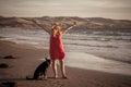 Happy attractive mature woman with her pet walking on friendly dog beach at sunset Royalty Free Stock Photo